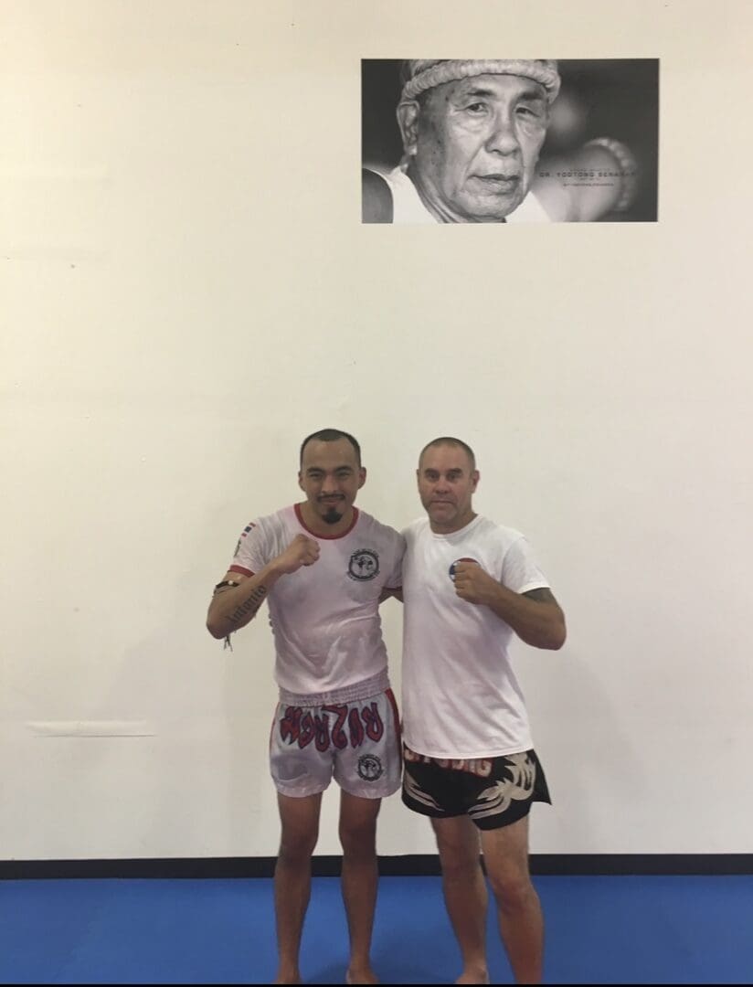 Two men posing in a martial arts gym.